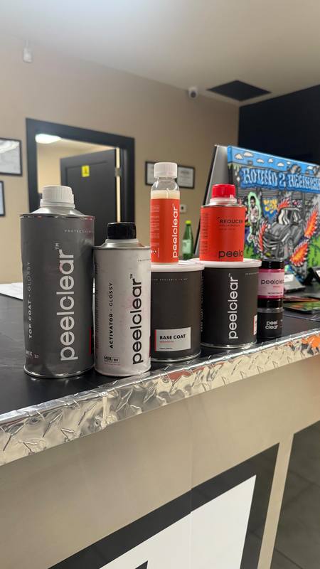 Peelclear tins lined up on the shop counter, top coat, activator, base coat and reducer, each marked with its mix ratio