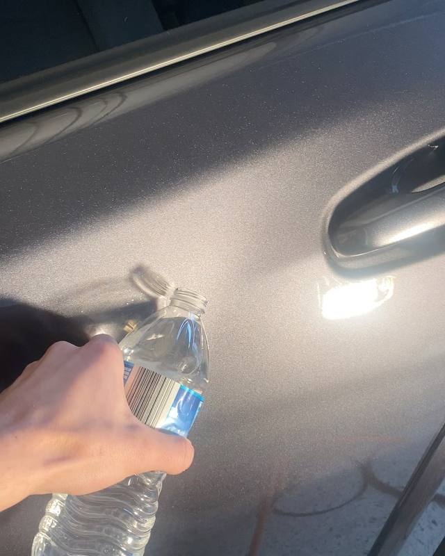 Water poured from a bottle onto the door of a ceramic-coated Toyota TRD Pro, pulling into tight round beads on the grey metallic panel instead of spreading across it