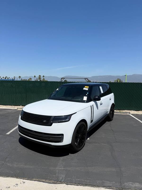 Range Rover in gloss white with the roof, pillars, grille, lower trim and wheels in black, the two-tone split running dead straight along the top of the glass; dealer paperwork still taped inside the windshield